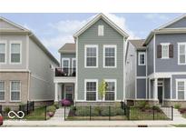 Charming two-story home with a manicured lawn, black fence, and a cozy front porch at 568 Lagerfield Dr, Carmel, IN 46032