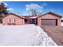 Charming single-story brick home with attached garage on a snowy day, promising cozy winter living at 1195 Chad Ct, Plainfield, IN 46168