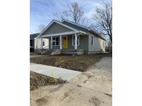 Charming home featuring a welcoming front porch, yellow door, and freshly mulched yard at 1237 E 29Th St, Anderson, IN 46016