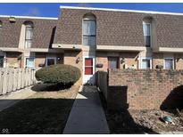 A charming townhome with a red brick facade, brown roofing, and well-maintained landscaping at 1344 Tishman Ln # 1344, Indianapolis, IN 46260