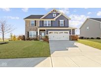Charming two-story home featuring a stone and blue siding exterior and an attached two car garage at 13615 Moorcroft Dr, Fishers, IN 46037