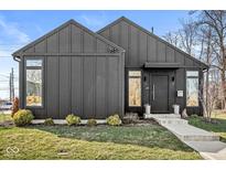 Modern home featuring dark vertical siding, a concrete walkway, and a well-manicured lawn at 1510 Columbia Ave, Indianapolis, IN 46202