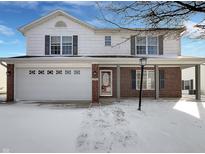 Charming two-story home featuring a brick facade, white siding, attached garage and covered porch in winter at 1846 Juniper Ln, Greenwood, IN 46143