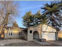 Charming single-story home with a stone facade and attached garage, surrounded by mature trees at 2204 Walnut Way, Noblesville, IN 46062