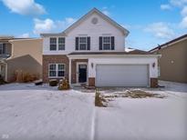 Charming two-story home with a brick facade and attached two-car garage, surrounded by a snowy lawn at 3153 Underwood Dr, Whiteland, IN 46184
