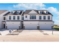 Beautiful new construction townhomes showcasing a modern white exterior with private garages and a bright blue sky at 3304 Morab Dr, Zionsville, IN 46077