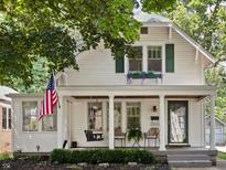 Charming two-story home featuring a covered front porch, swing, and an American flag at 5426 Broadway St, Indianapolis, IN 46220