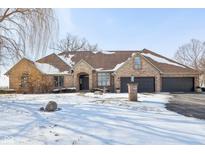 Exterior view of brick home with three-car garage, mature trees, and a snowy yard at 6024 N County Road 50 W, Lizton, IN 46149