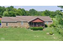 Charming brick home with a well-manicured lawn, inviting front porch, and a backdrop of lush trees at 7152 Old Morgantown Rd, Martinsville, IN 46151