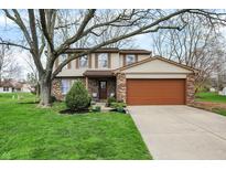 Charming two-story home featuring a brick facade, attached two-car garage and well-manicured lawn at 7344 Monon Cir, Indianapolis, IN 46256