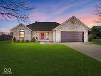 Charming brick home featuring a well-manicured lawn and attached two-car garage at 1027 Summer Way Dr, Shelbyville, IN 46176