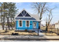 Charming blue home with black trim, fenced yard, and landscaped front on a sunny day at 1134 S Illinois St, Indianapolis, IN 46225