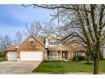 Charming two-story brick home featuring an attached garage and a well-manicured front lawn at 12512 Geist Cove Dr, Indianapolis, IN 46236