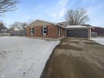Brick home features a two-car garage, well-maintained landscaping, and a concrete driveway at 1546 Becket Dr, Shelbyville, IN 46176
