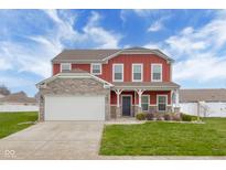 Charming two-story red home featuring a stone facade and well-manicured lawn at 2016 Woodland Parks Dr, Columbus, IN 47201