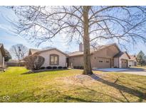 Charming brick home featuring attached garages, well-kept landscaping, and mature shade trees on a sunny day at 3535 Woodglen Way, Anderson, IN 46011