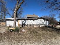 Dilapidated white garage with partially boarded windows in a neglected backyard with dead grass and weeds at 396 S Audubon Rd, Indianapolis, IN 46219