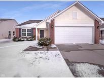 Charming single-Gathering home featuring a two-car garage and brick accents on a snow-covered lot at 4943 Dunlin Dr, Indianapolis, IN 46235