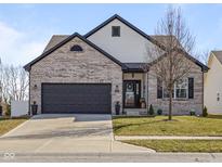 Charming two-story home featuring a grey brick facade, dark trim, a manicured lawn, and a two-car garage at 553 Farnham Dr, Westfield, IN 46074