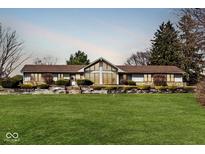 Ranch-style home featuring a well-manicured front yard, large windows, and mature landscaping at 6114 Brokenhurst Rd, Indianapolis, IN 46220