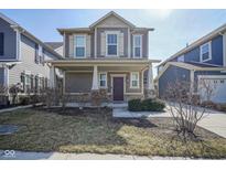 Charming two-story home featuring a covered front porch, a well-maintained lawn, and a welcoming entrance, perfect for curb appeal at 7228 Broadacre Ct, Carmel, IN 46033