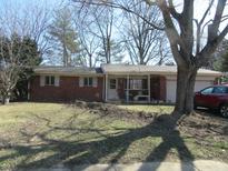 Charming brick ranch-style home with a covered front porch and attached garage, and mature landscaping at 7625 Partridge Rd, Indianapolis, IN 46227
