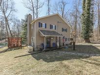 Inviting two-story home featuring blue shutters, covered porch, and lush natural surroundings at 8460 S Green Dr, Nineveh, IN 46164