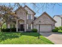 Charming brick home with a two-car garage, arched entryway, and well-manicured lawn at 10576 Greenway Dr, Fishers, IN 46037