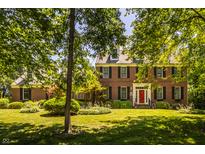 Charming brick home featuring a bright red front door and well-manicured landscaping at 1409 S Harmony Trl, Greenfield, IN 46140