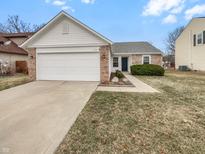 Charming single-story home featuring a brick and white vinyl facade, attached garage, and well-maintained landscaping at 1914 Kingen Dr, Greenfield, IN 46140
