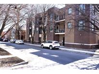 Street view of a red brick apartment building with balconies and cars parked along the curb at 233 E St Joseph St # 3H, Indianapolis, IN 46202