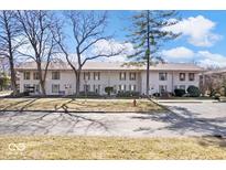 Two-story townhome showing a landscaped yard with mature trees and a sidewalk at 4307 Dahlia Ct, Indianapolis, IN 46220