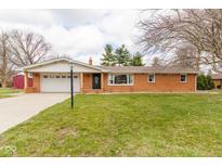Charming single-story brick home with attached garage, lovely front yard, and mature trees in a peaceful setting at 518 Wedgewood Dr, Anderson, IN 46013