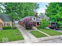 Charming brick home with a manicured lawn, lush trees, and a long driveway leading to a detached garage at 6162 Carrollton Ave, Indianapolis, IN 46220