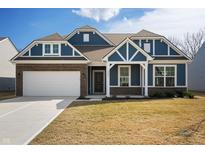 Charming home featuring blue siding, brick accents, covered porch, and a two-car garage at 9839 Canyon Ln, Pendleton, IN 46064