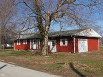 Charming red home featuring white trim, a well-manicured lawn, and a picturesque tree in the front yard at 210 Evergreen St, Morgantown, IN 46160
