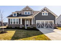 Charming two-story home with gray siding, brick accents, and a two-car garage at 14879 Thornapple Dr, Carmel, IN 46032