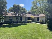 Well-maintained one-story home boasts a lush green lawn and mature shade trees at 5515 Shorewood Dr, Indianapolis, IN 46220
