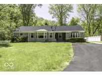Charming single-story home featuring stone accents, a well-manicured lawn, and a paved driveway surrounded by mature trees at 6204 S Madison Ave, Indianapolis, IN 46227