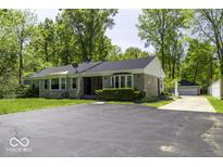 Charming single-story home featuring a stone facade, mature trees, and a spacious asphalt driveway at 6204 S Madison Ave, Indianapolis, IN 46227