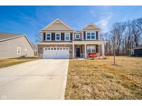 Charming two-story home with a two-car garage, covered porch with red chairs, and a well-manicured lawn at 6699 Dunkirk Dr, McCordsville, IN 46055