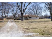 Ranch style home with a long gravel driveway and mature trees in a country setting at 8647 Cox Rd, Indianapolis, IN 46221
