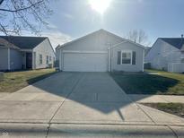 Charming single-Gathering home showcasing a driveway, garage, and gray siding at 13250 N Brick Chapel Dr, Camby, IN 46113