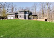 Beautifully landscaped, gray two-story home with a large, lush green lawn and a three car garage at 534 1/2 Amos Dr, Zionsville, IN 46077