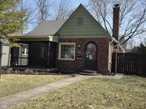 Charming brick home with a screened-in porch, arched front door, and well-maintained lawn at 5915 Winthrop Ave, Indianapolis, IN 46220