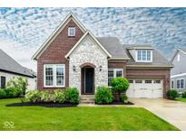 Charming brick home featuring a stone facade, manicured lawn, and a welcoming three-car garage at 12167 Ams Run, Carmel, IN 46032