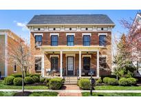Charming brick home with a welcoming front porch, lush landscaping, and a well-manicured lawn at 13018 Deerstyne Green St, Carmel, IN 46032