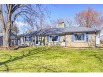 Charming stone-clad ranch home features a well-maintained lawn, blue shutters and mature shade trees at 7816 E St Joseph St, Indianapolis, IN 46219