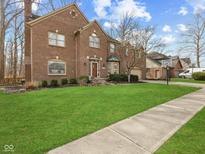 Charming two-story brick home with a well-manicured lawn, lush green grass, and walkway at 10145 Northwind Dr, Indianapolis, IN 46256