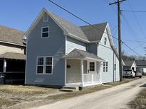 Charming two-story home with light blue siding and a welcoming front porch with white railings at 117 N 10Th St, Elwood, IN 46036